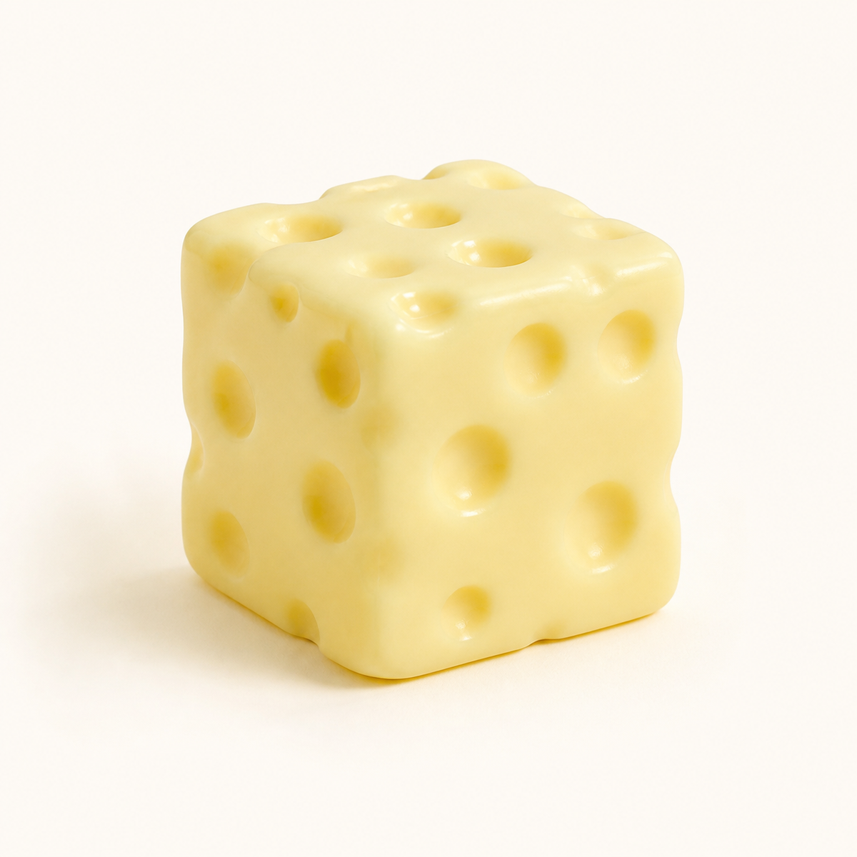 Pale yellow cheese cube squishy with rounded holes on a warm white background