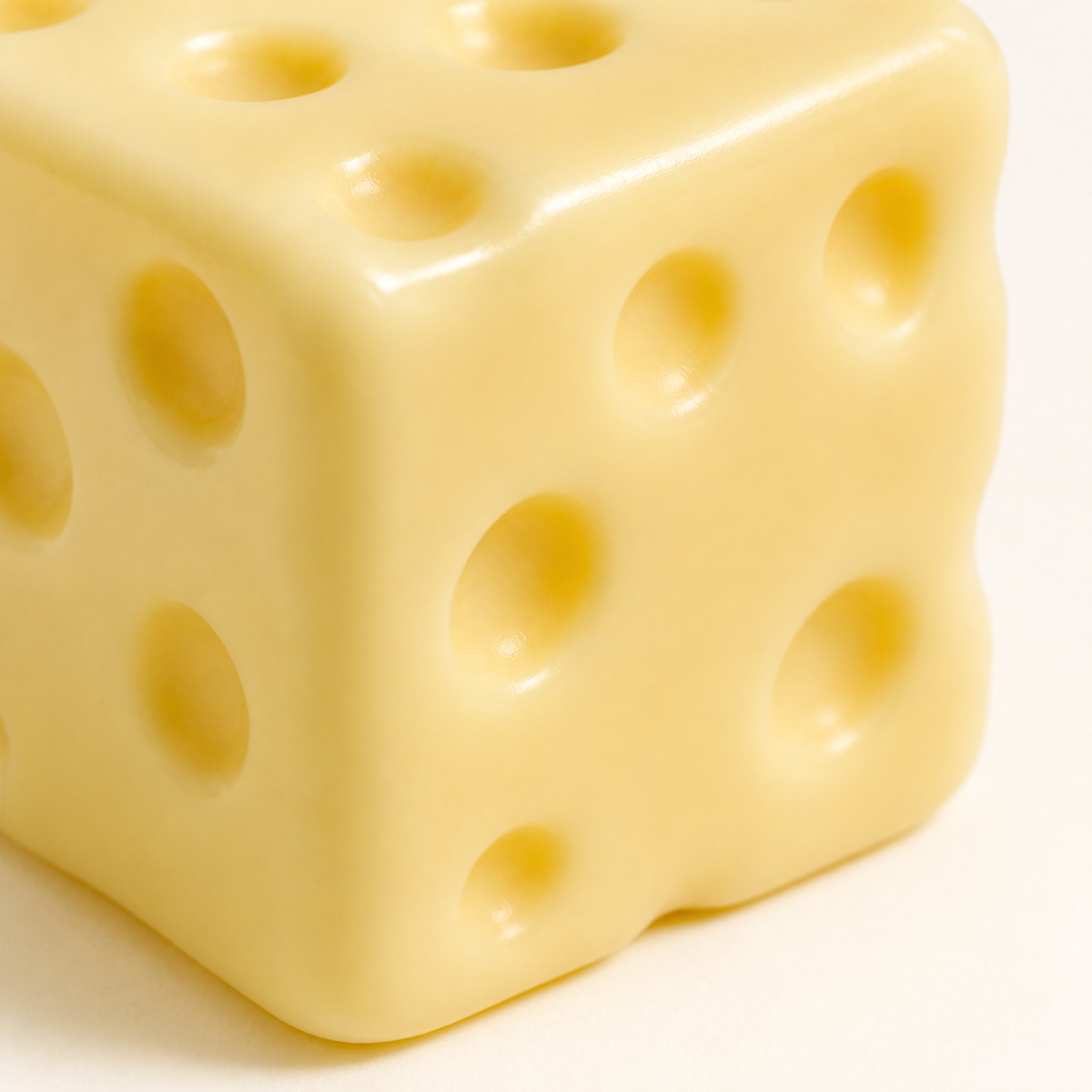 Close-up of the rounded holes and soft edges of the pale yellow cheese cube squishy