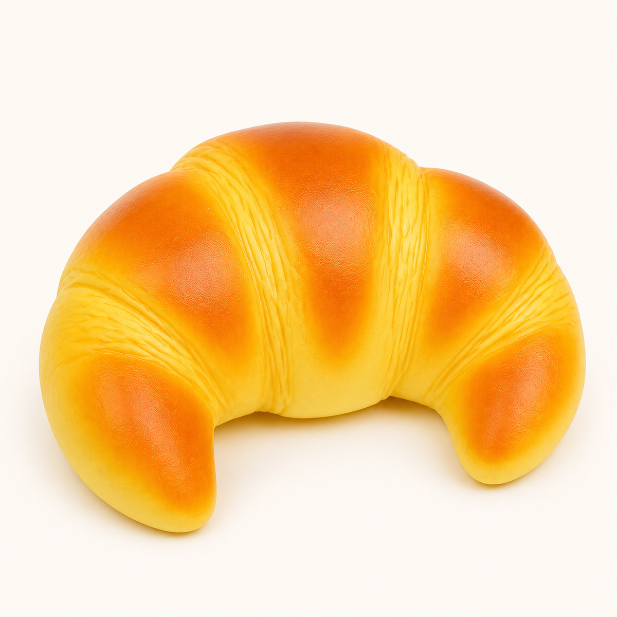 Croissant slow-rise squishy toy on a cream background
