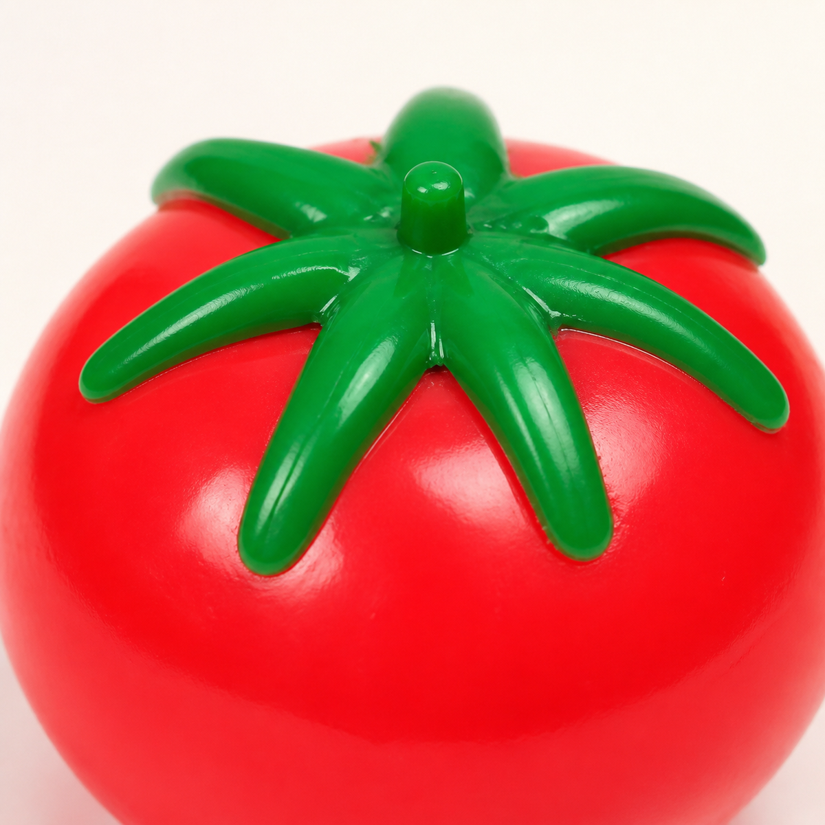 Close detail of the Tomato Splat Squeeze Toy leafy cap and red body